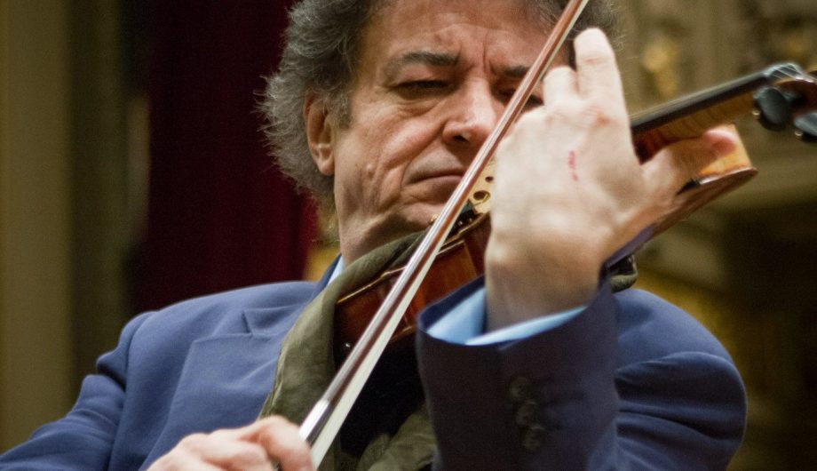 close up of eugen sarbu playing the violin wearing a dark blue suit