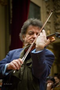 a photograph of Euguen Sarbu in a dark blue suit playing the violin