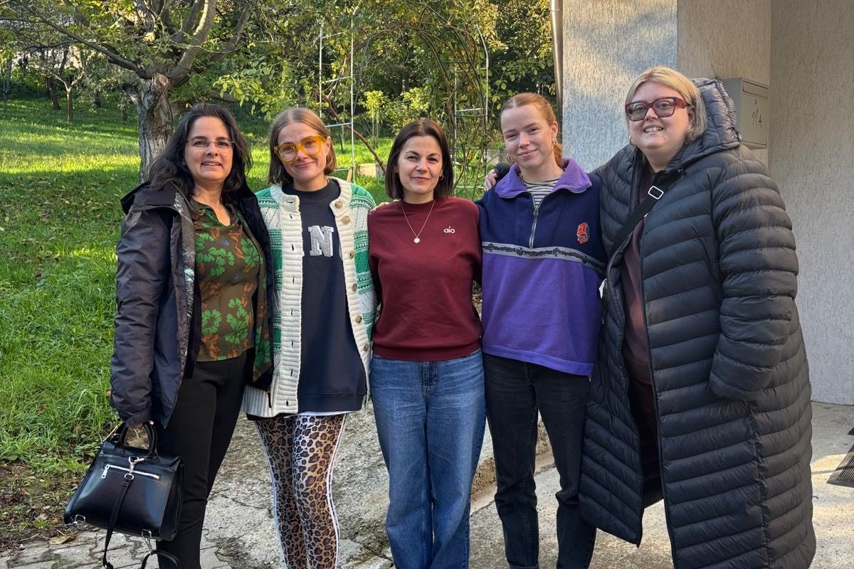 a group of five people standing next to each of smiling for the camera. There is a tree in the background