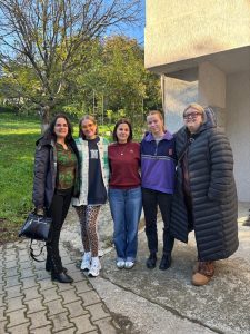 a group of five people standing next to each of smiling for the camera. There is a tree in the background